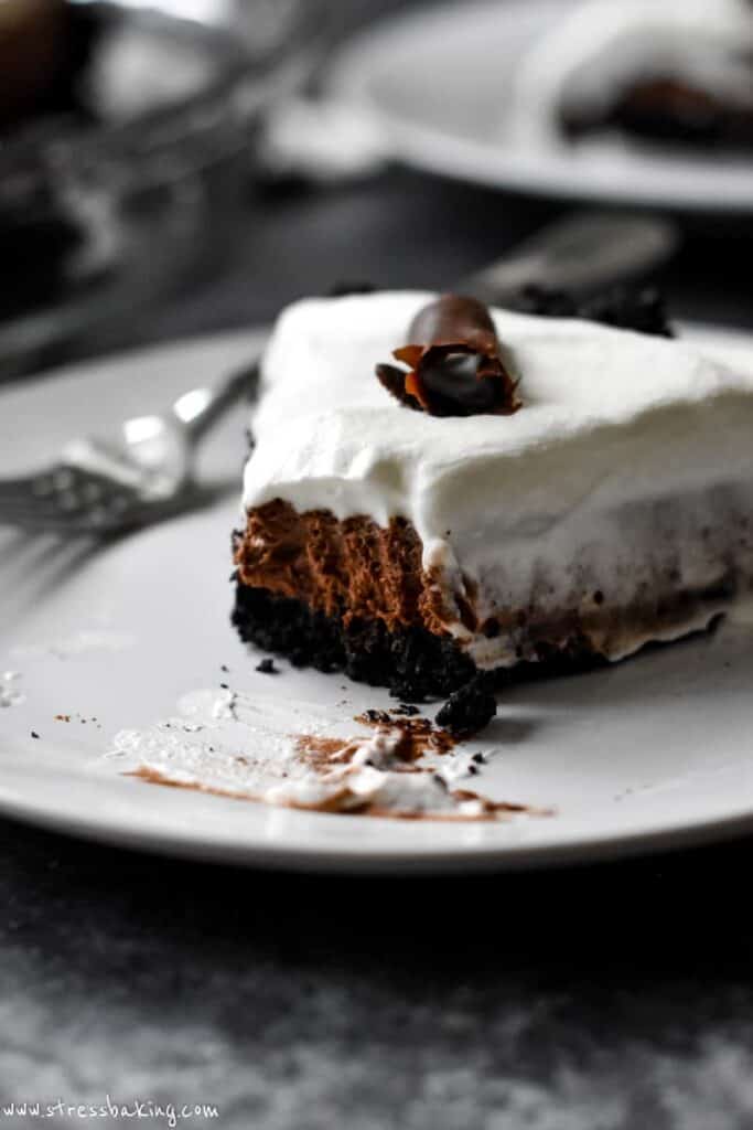A slice of Bailey's chocolate pie topped with whipped cream and chocolate shavings with a fork on a white plate