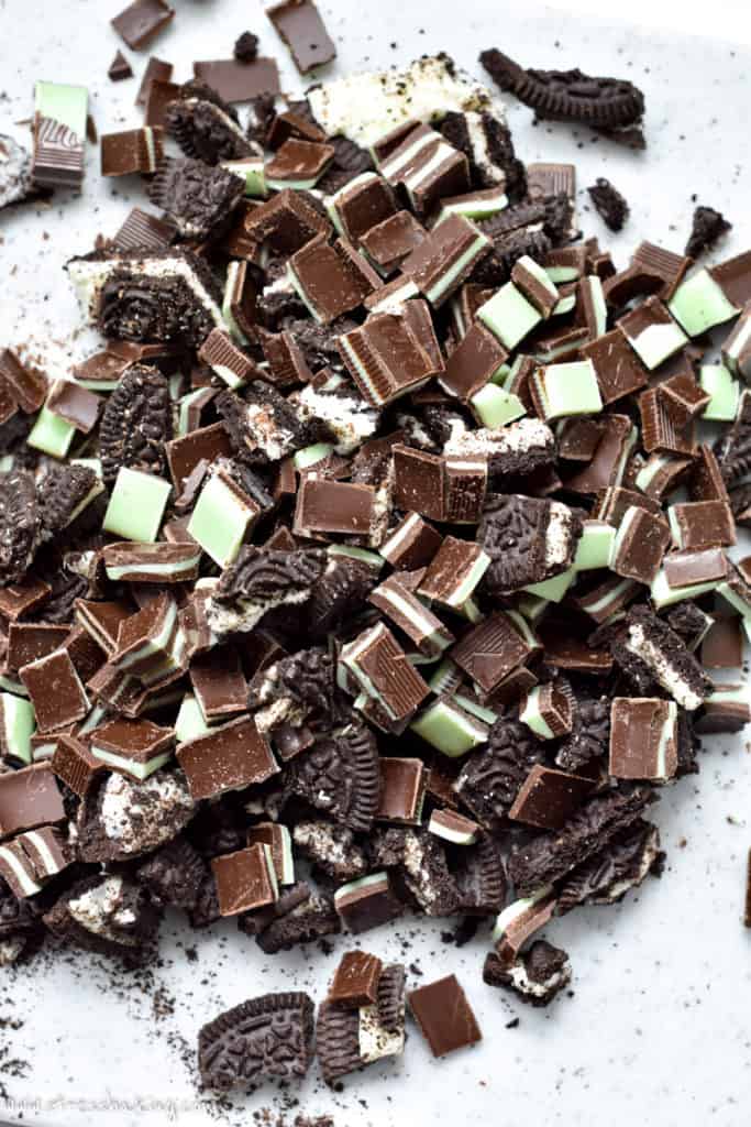 A pile of chopped Andes mints and Oreo cookies on a cutting board