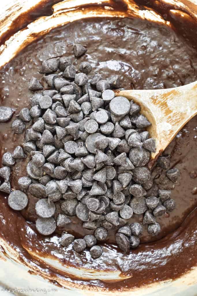 A bowl of brownie batter with a pile of chocolate chips