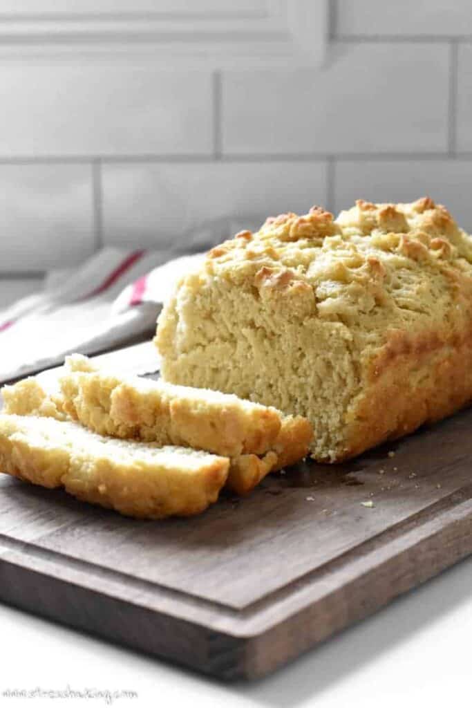 A loaf of golden beer bread with a few slices cut