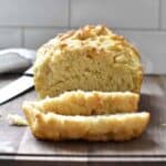 Close up on golden, crackled beer bread crust with a slice cut