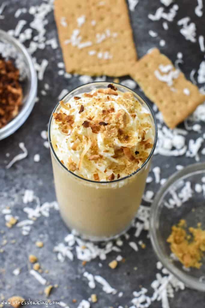A coconut cream pie milkshake topped with toasted coconut and graham cracker crumbles