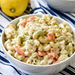 A white bowl of pasta salad on a blue and white dish towel