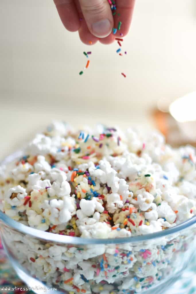 Sprinkles being dropped onto a bowl of funfetti popcorn