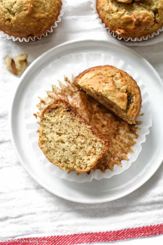 A banana muffin sliced in half on a white plate