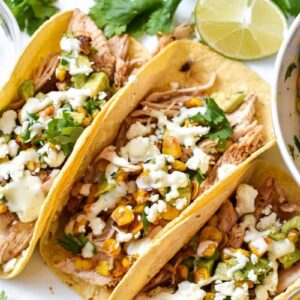Three mexican street corn tacos on a white platter