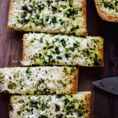 cheesy slices of garlic bread on a cutting board