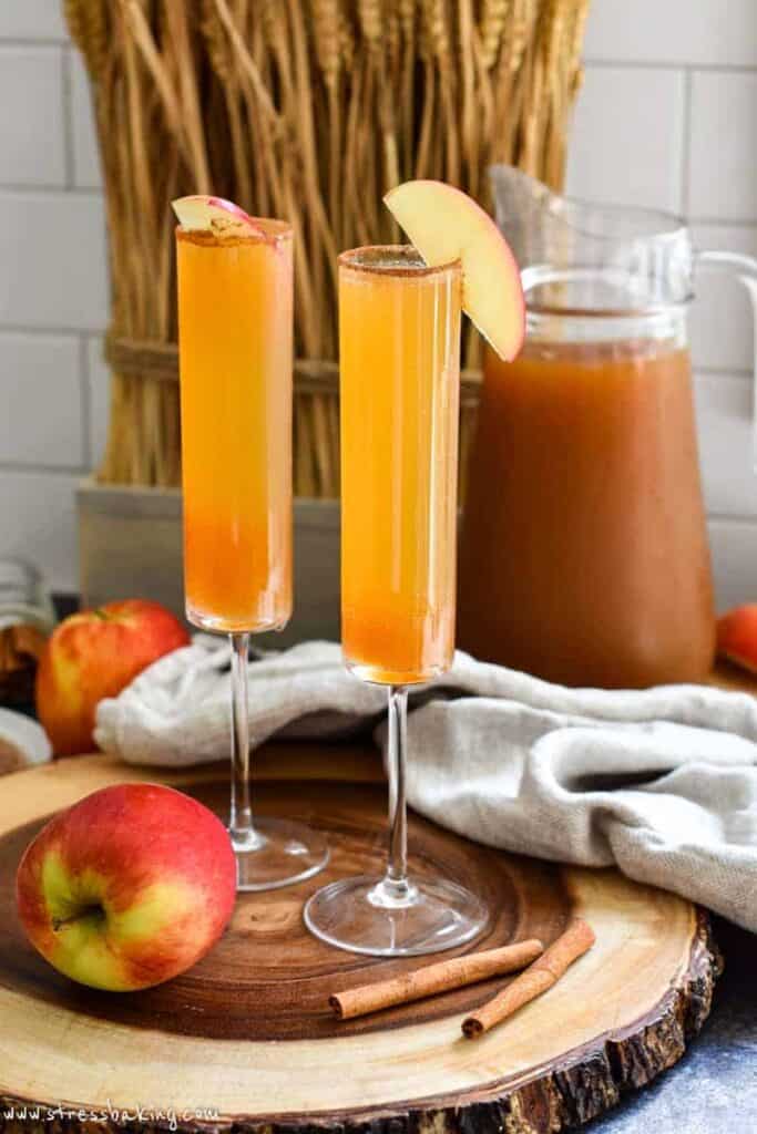Two apple cider champagne cocktails in a fall setting