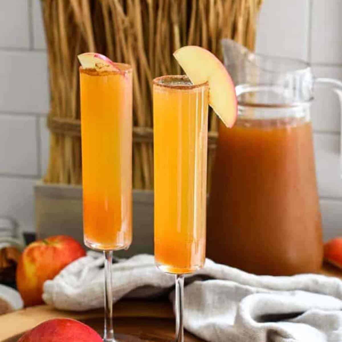 Two apple cider champagne cocktails in a fall setting