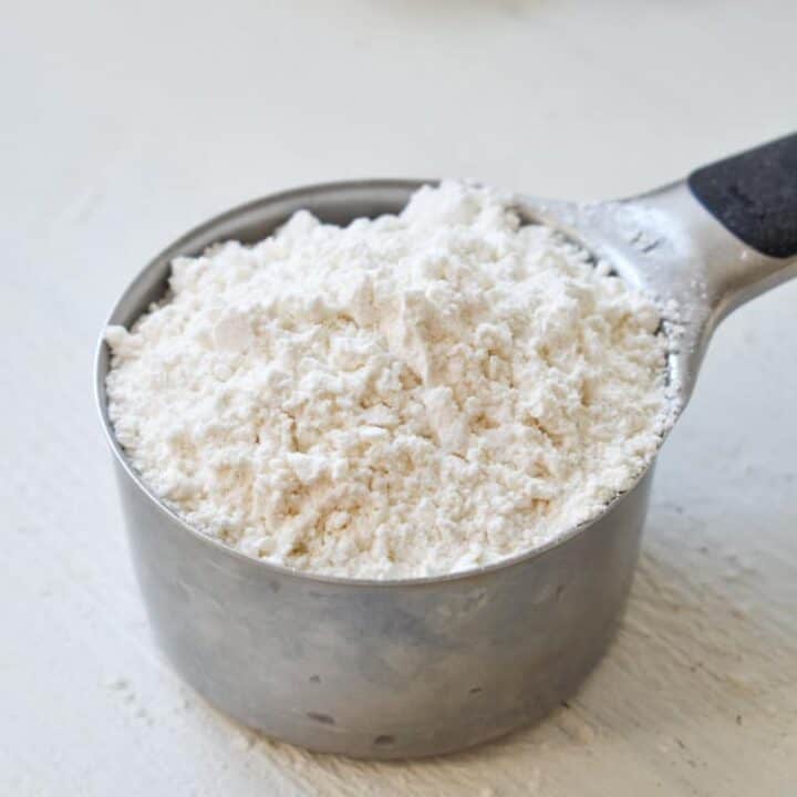 A measuring cup full of a mound of cake flour