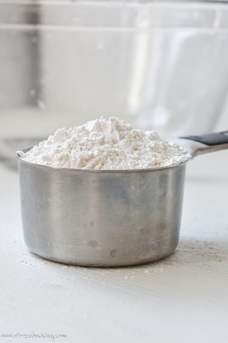 Side shot of a measuring cup of flour showing it mounded over the top