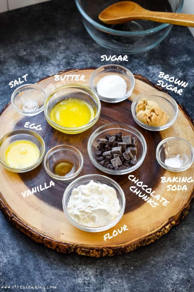 A wooden platter full of the ingredients for a giant chocolate chip cookie with each one labeled