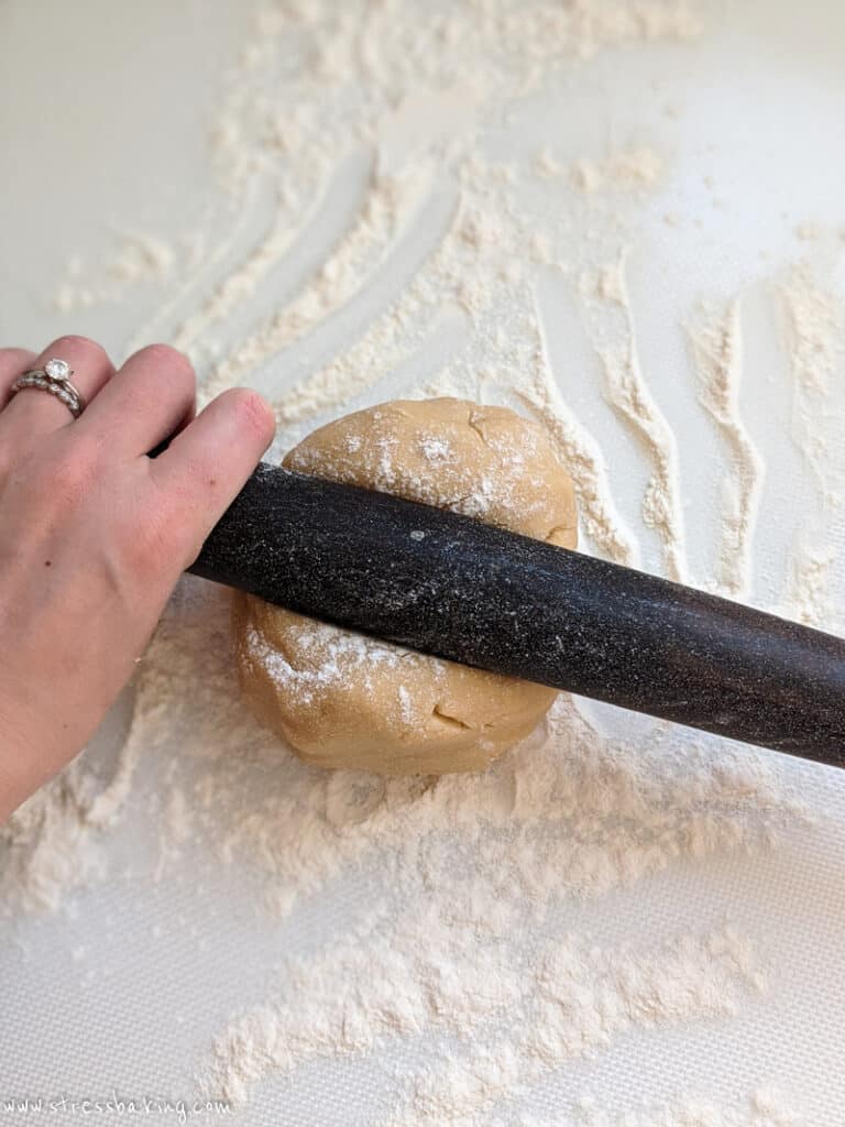 A round of cookie dough being rolled out on a floured surface