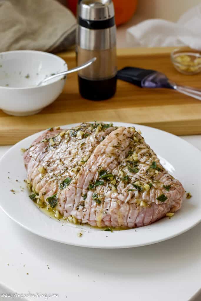 A turkey breast coated in seasonings and ready to be cooked