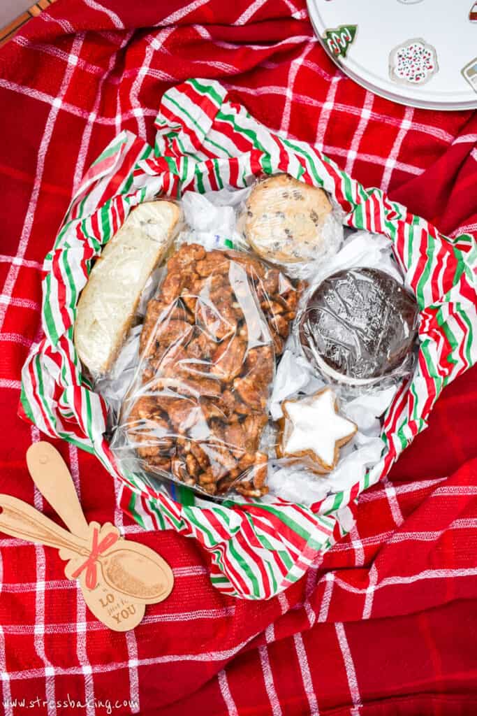 Holiday tin full of wrapped cookies, nuts and biscotti on a red tablecloth