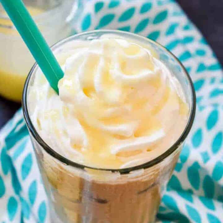 Iced white mocha in a clear glass topped with whipped cream and a teal straw