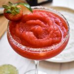 A smooth, blended strawberry margarita with strawberry and lime garnish close up