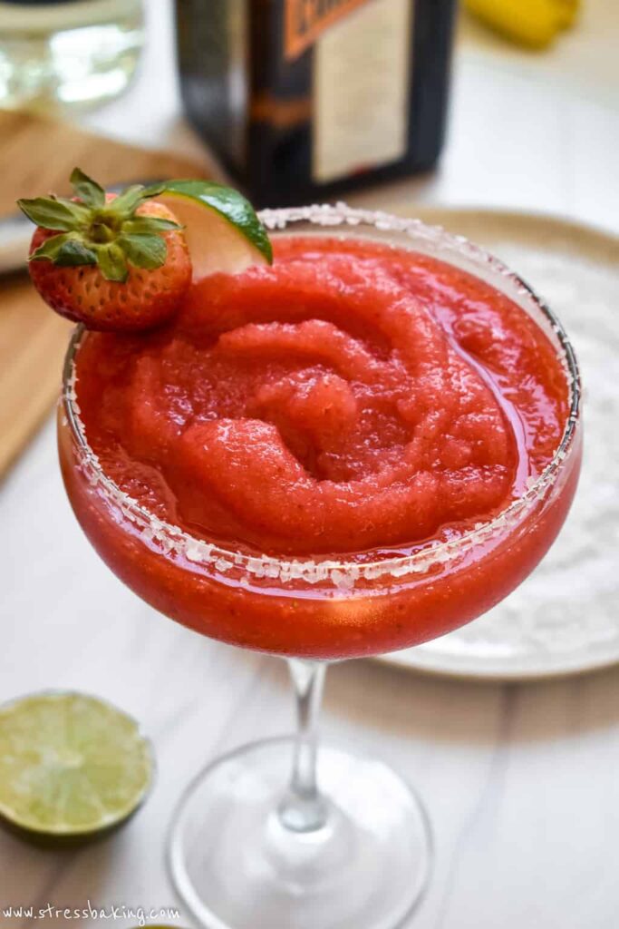 A smooth, blended strawberry margarita with strawberry and lime garnish close up