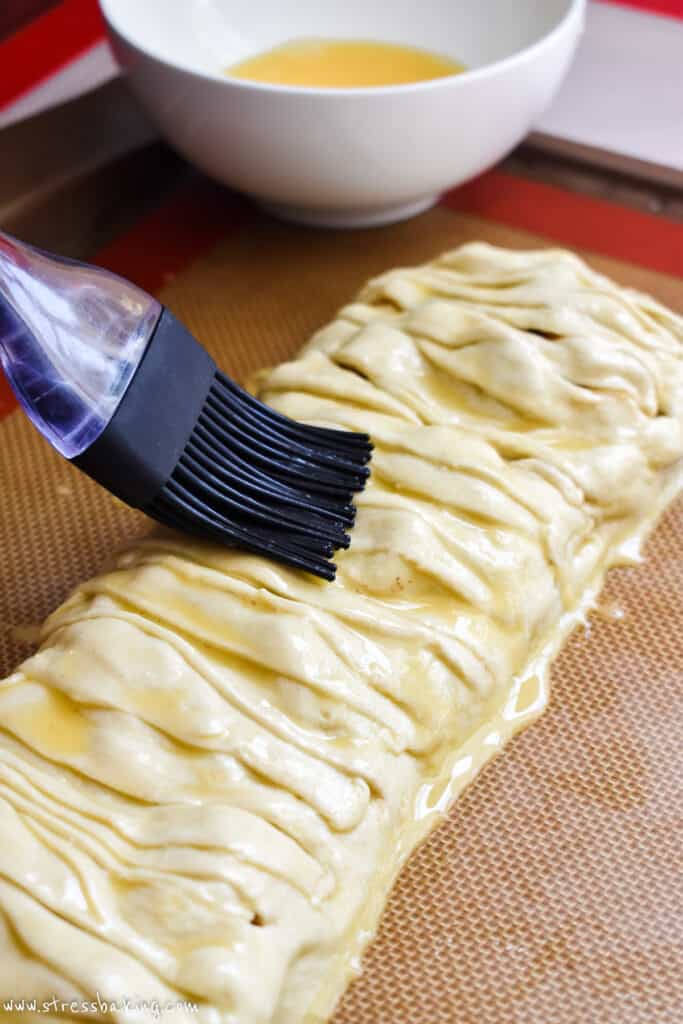 Egg wash being brushed over the top of apple strudel pastry