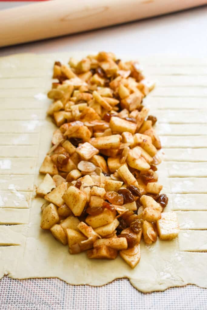 Apple strudel filling down the middle of a prepared puff pastry