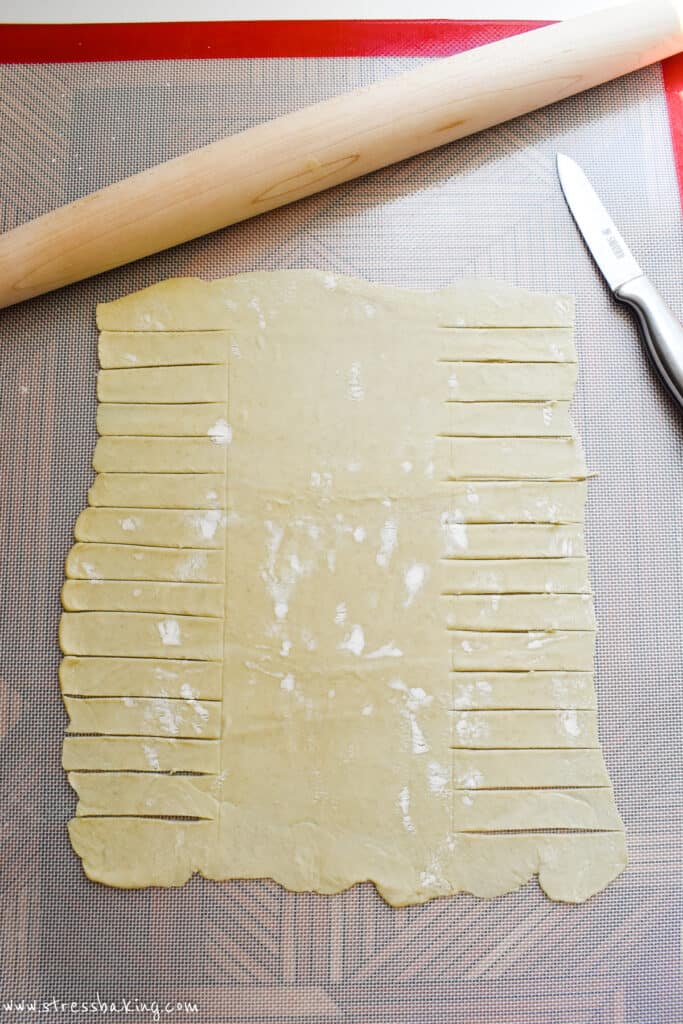 Puff pastry rolled out and sliced on a pastry mat