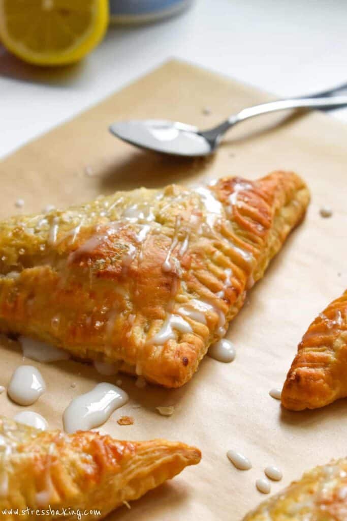 Closeup of apple turnovers on parchment paper drizzled with icing