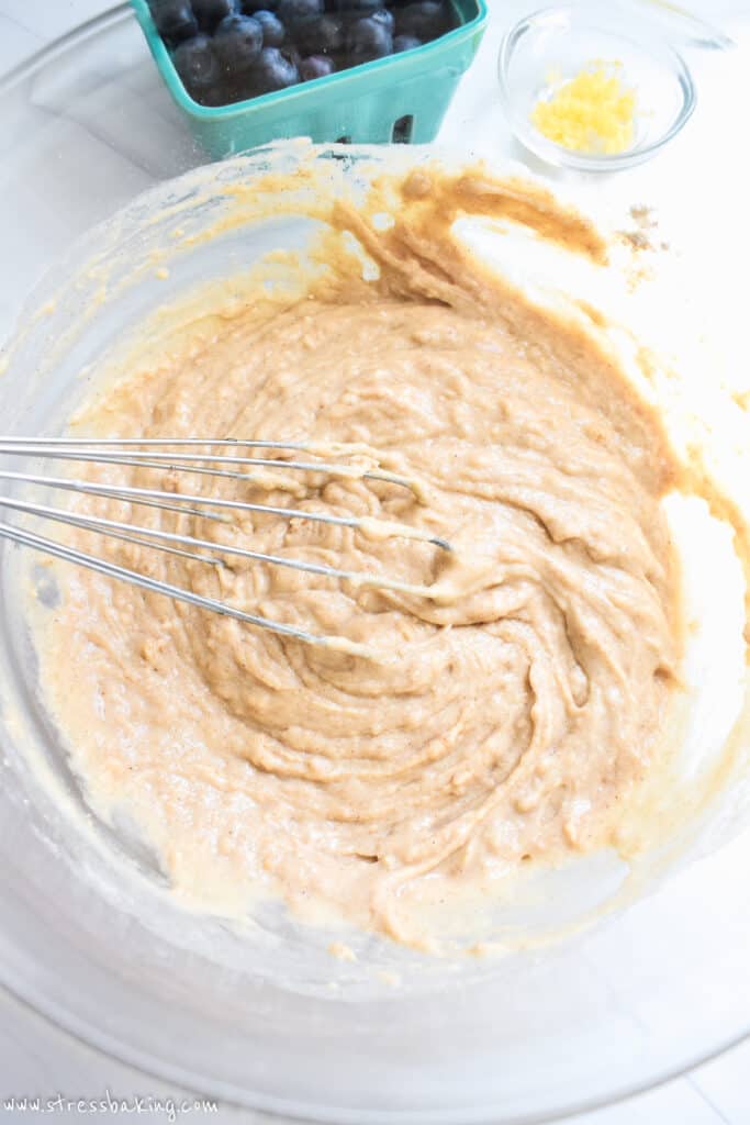 Glass bowl full of tan batter with a whisk