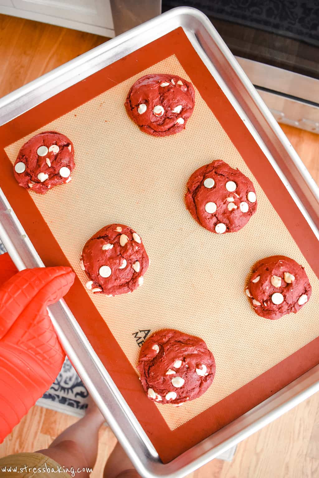 Freshly baked red velvet cookies with white chocolate chips on a baking sheet