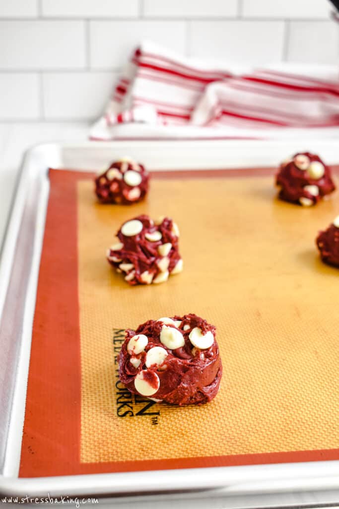 Bright red cookie dough dotted with white chocolate chips on a baking sheet