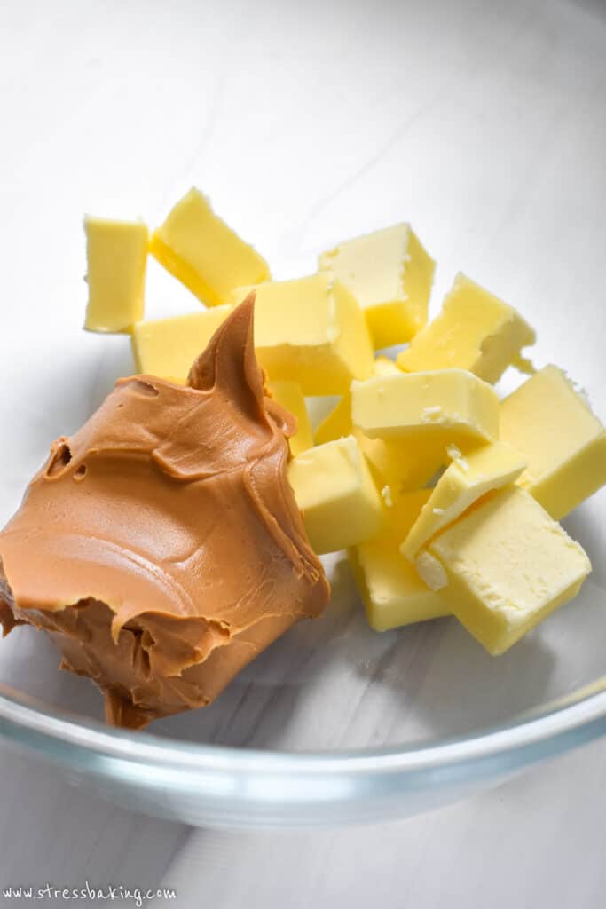 Tabs of yellow butter and peanut butter in a clear mixing bowl