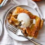Overshot shot of a slice of apple pie with a golden brown crust and topped with vanilla ice cream