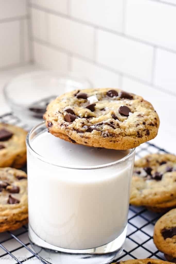 A chocolate chip cookie on top of a glass of milk