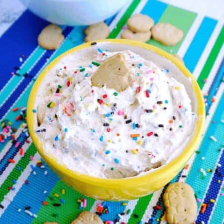 Dunkaroo Dip in a bright yellow bowl topped with sprinkles and an animal cracker
