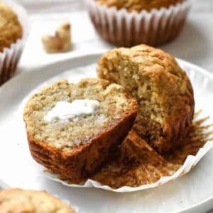 A banana muffin sliced in half with a melted tab of butter