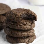 Stack of crinkly brownie cookies with a bite taken out to show the fudgy center