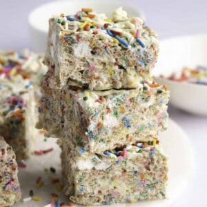 Stack of brightly colored funfetti rice krispie treats drizzle with white chocolate and sprinkles