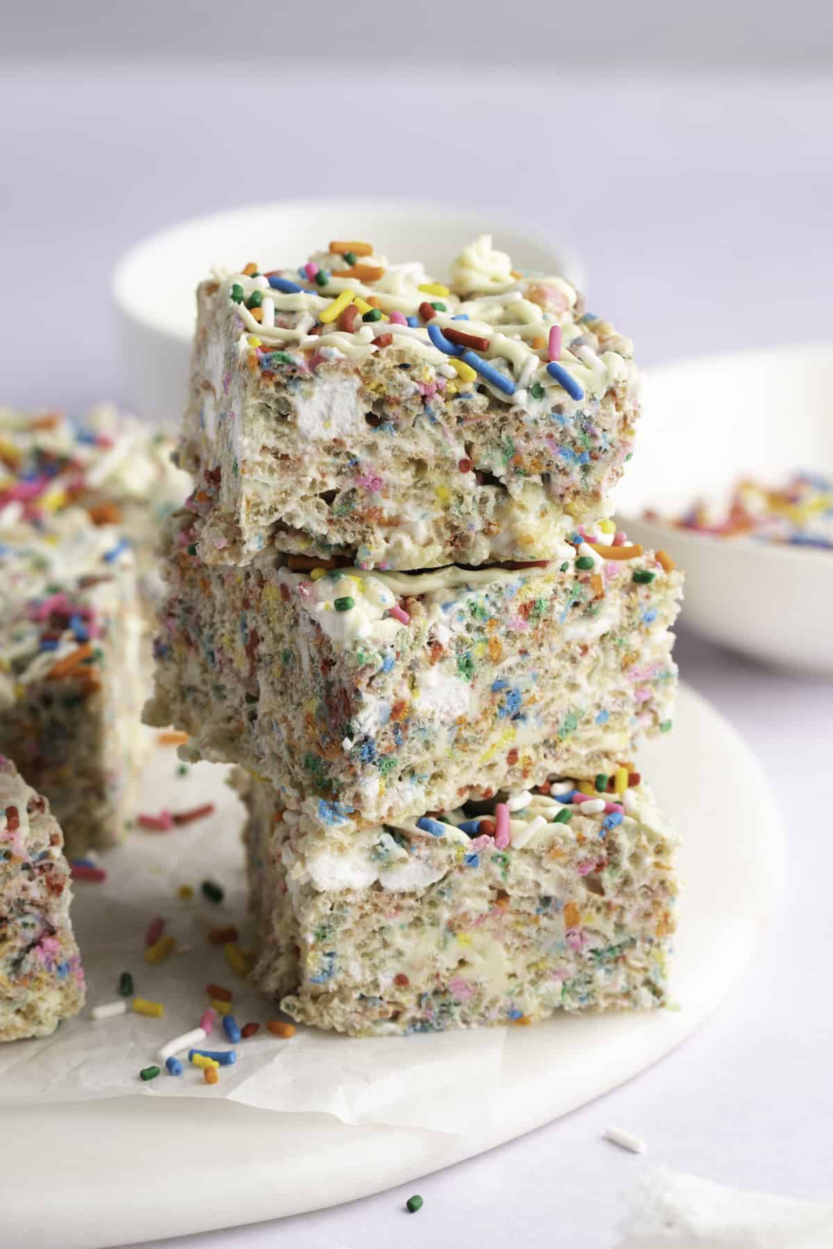 Stack of brightly colored funfetti rice krispie treats drizzle with white chocolate and sprinkles