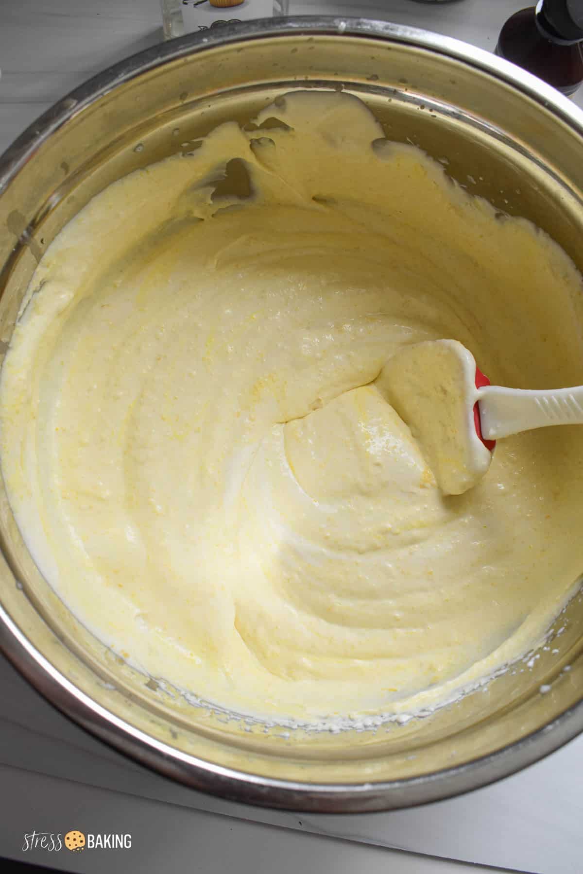 Pale yellow corn ice cream batter in a silver mixing bowl with a spatula