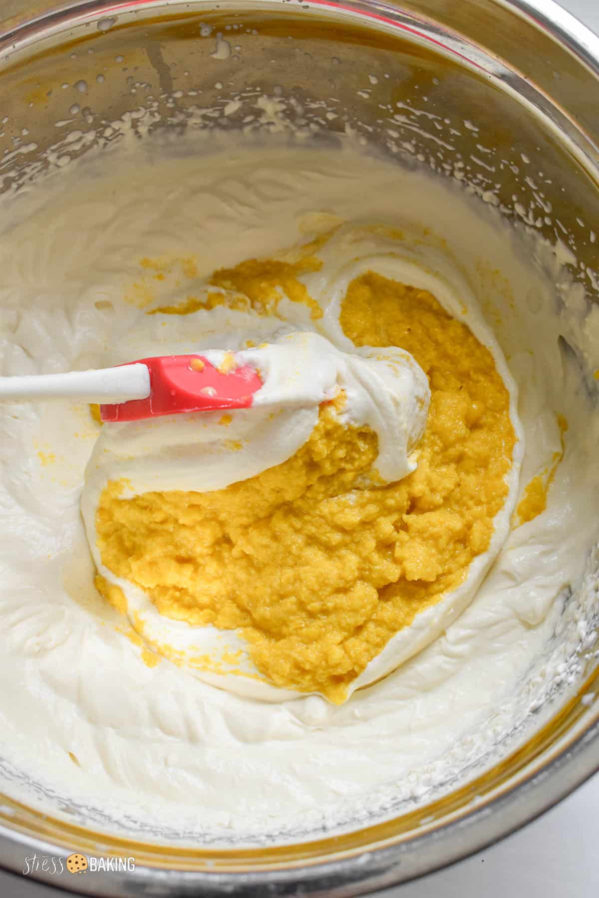 Bright yellow corn puree being folded into white cream mixture
