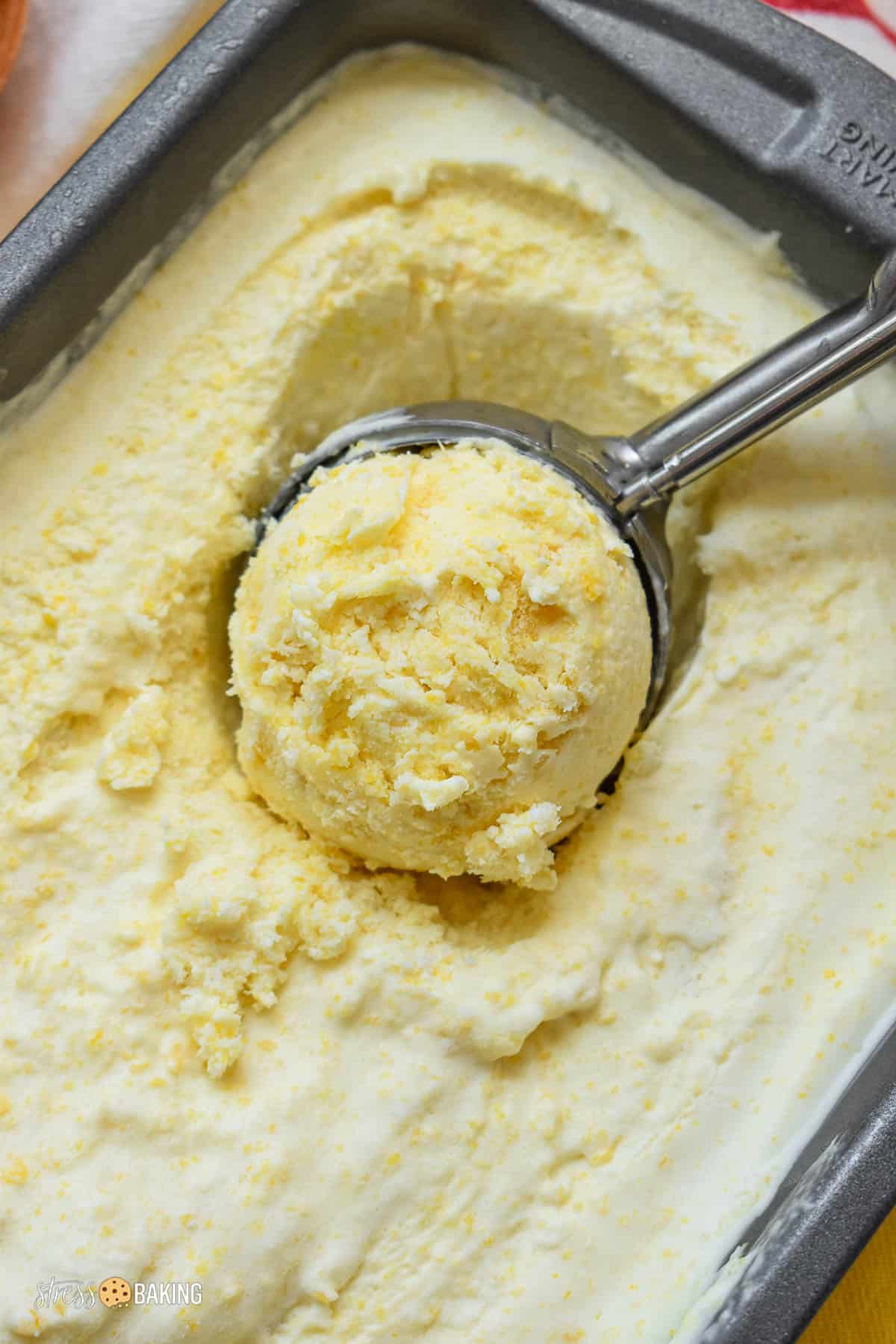 Yellow corn ice cream being scooped out of a loaf pan