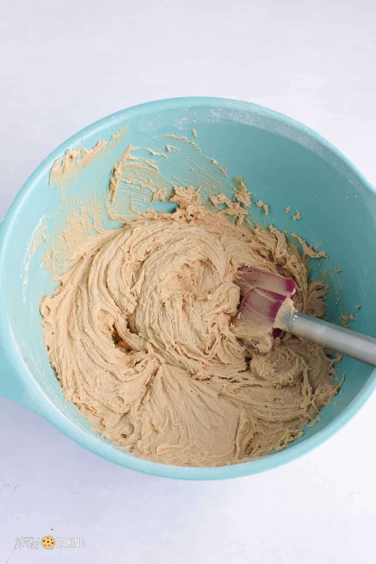 Tan batter mixture in a teal mixing bowl with a spatula