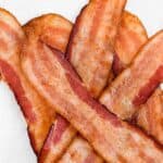 Golden brown crispy bacon slices piled on a paper towel