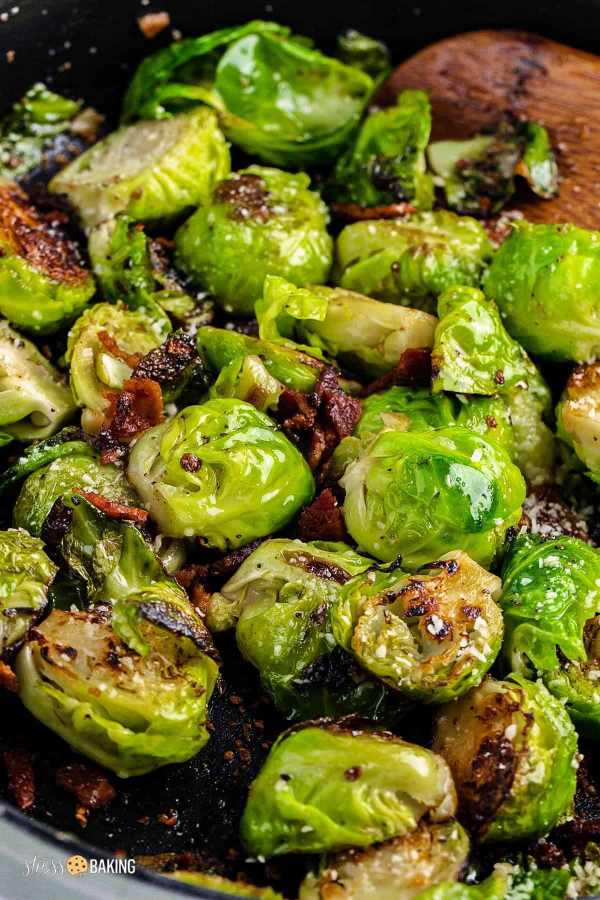 Halved brussels sprouts and bacon in a skillet and topped with parmesan cheese