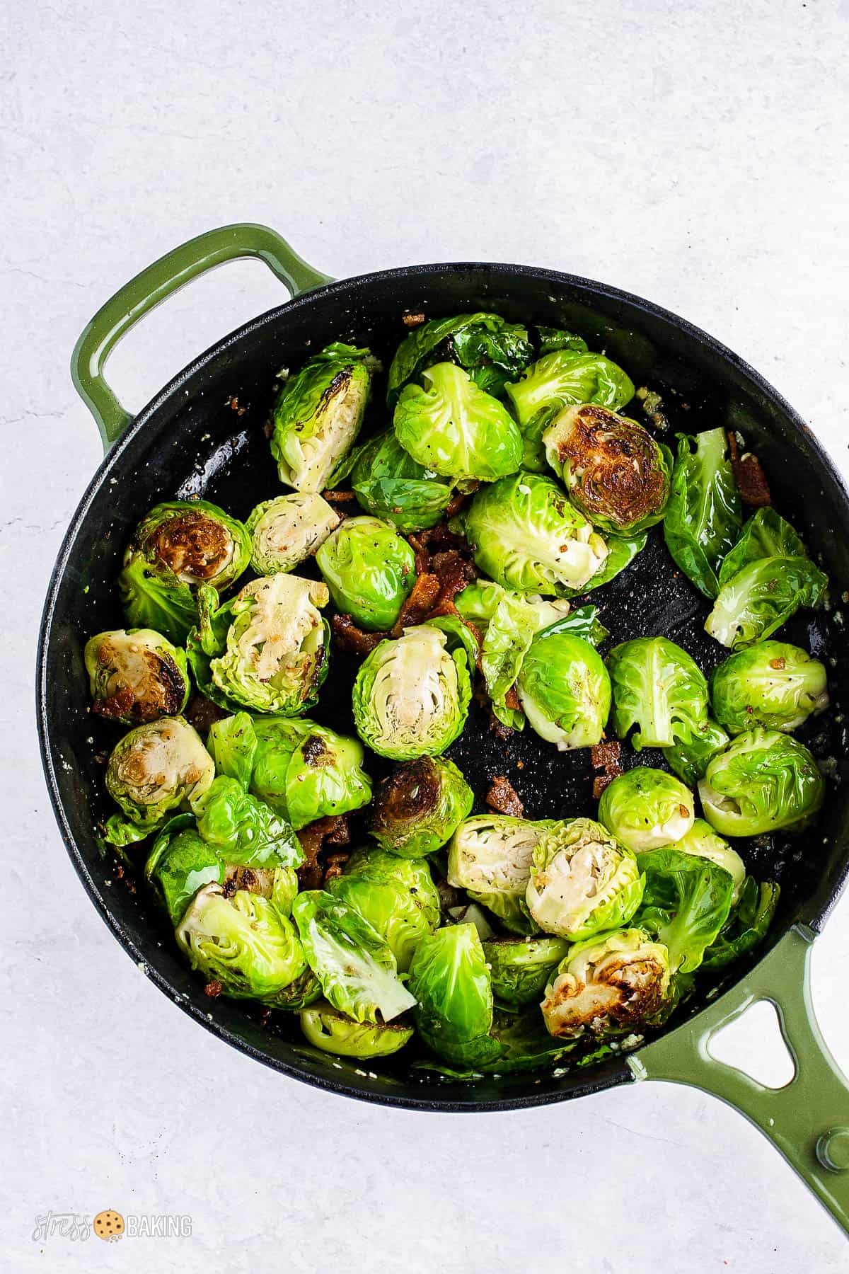 Halved brussels sprouts and bacon being browned in a skillet