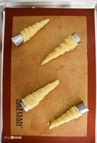 Metal pastry cones wrapped with puff pastry and brushed with an egg wash