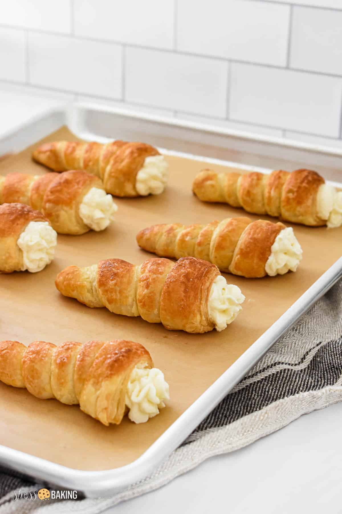 Pastry cones filled with cream on a baking sheet