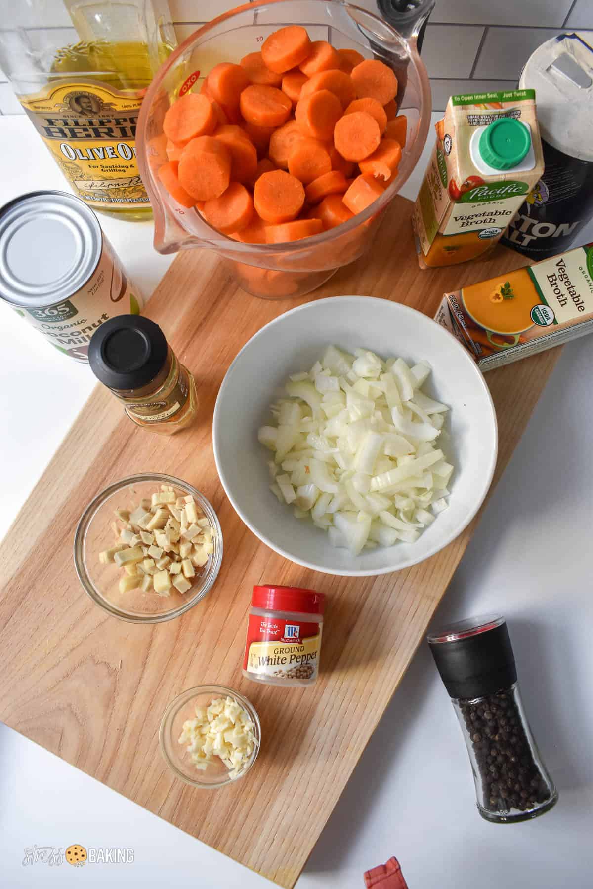 Ingredients for carrot ginger soup in different containers atop a cutting board