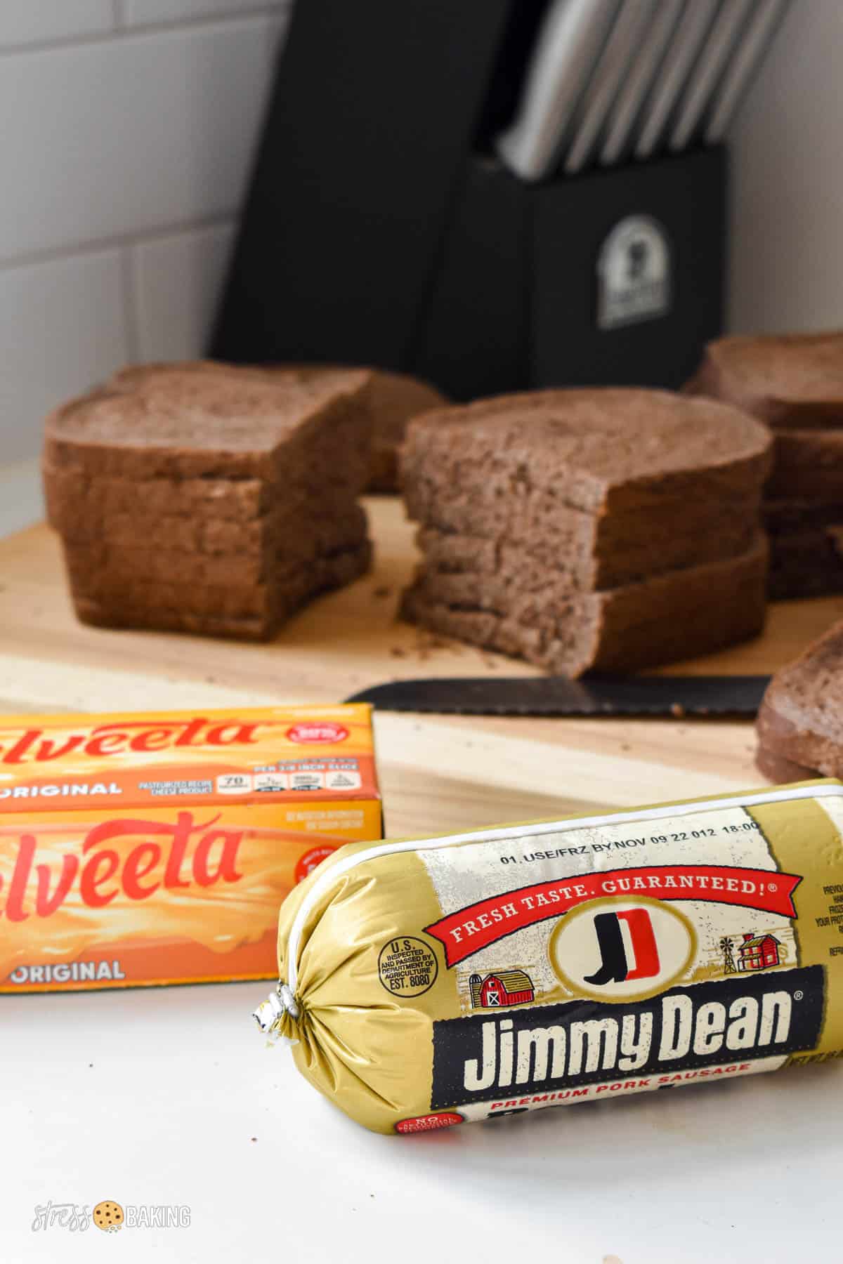 Jimmy Dean pork sausage and Velveeta next to a cutting board full of pumpernickel bread slices