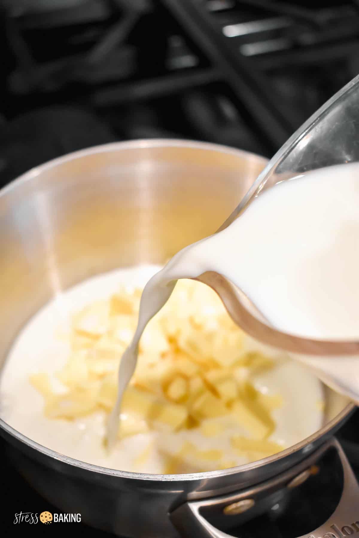 Milk being poured into a saucepan of chopped white chocolate