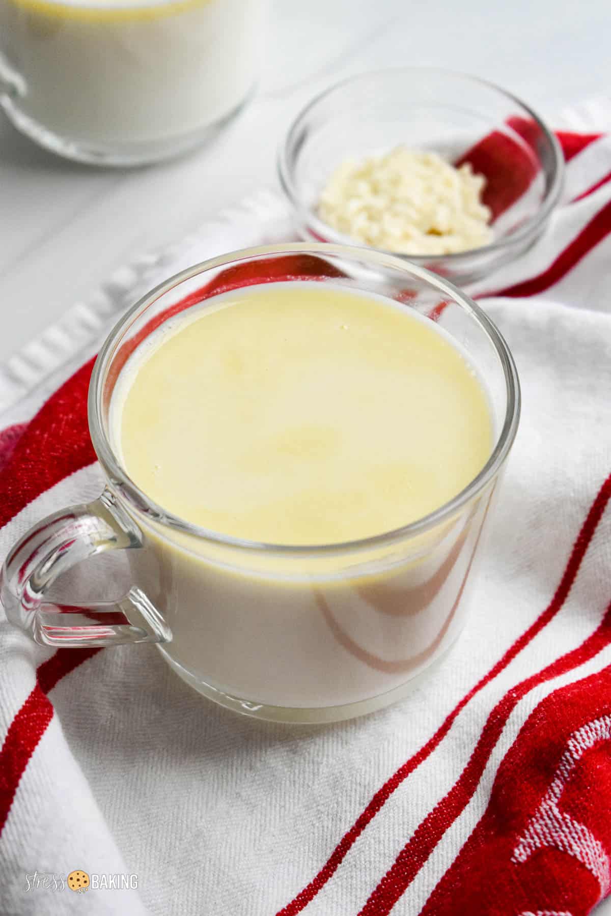 White hot chocolate in a clear mug on a red and white dish towel